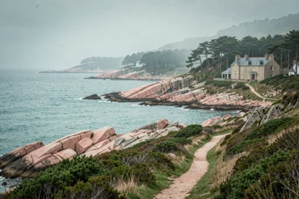 Paysage côtier breton avec rochers de granite rose et hôtel en pierre niché dans les pins maritimes des Côtes-d'Armor